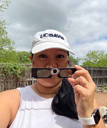 Karla Fung in ֱ hat holds up eclipse glasses