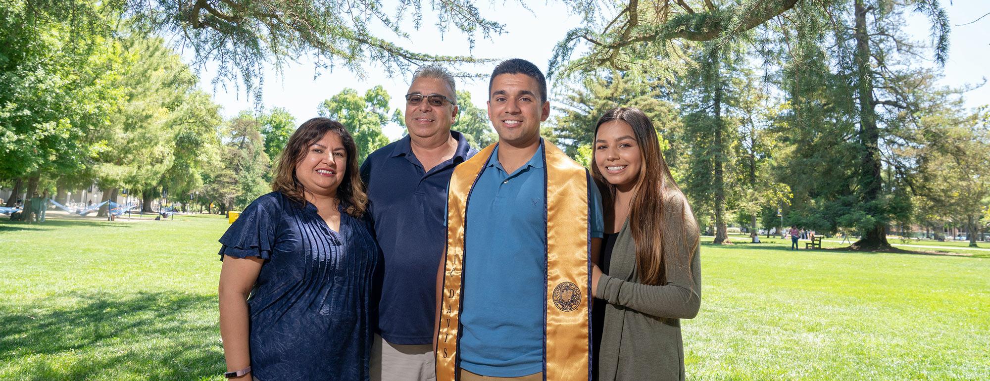 Parents pose with their ֱ graduate son on the quad 
