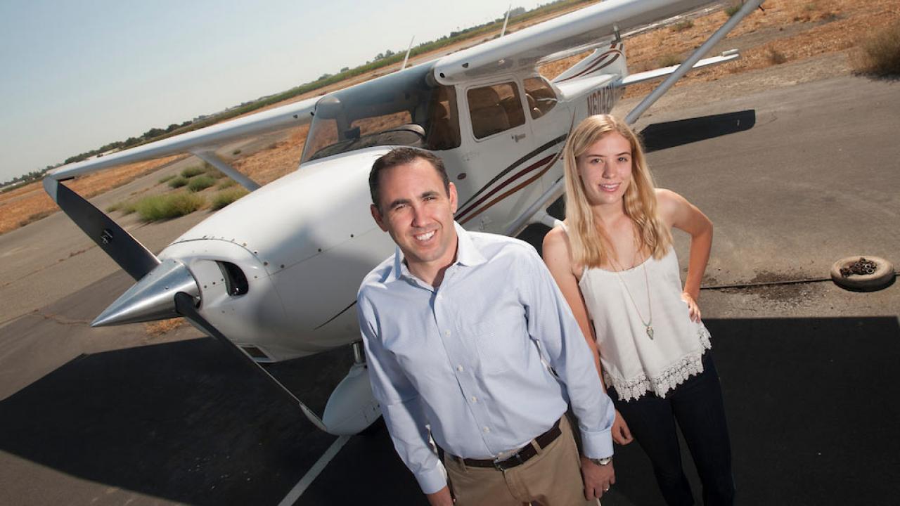 An instructor and student pose for a shot in front of an airplane at ֱ airport