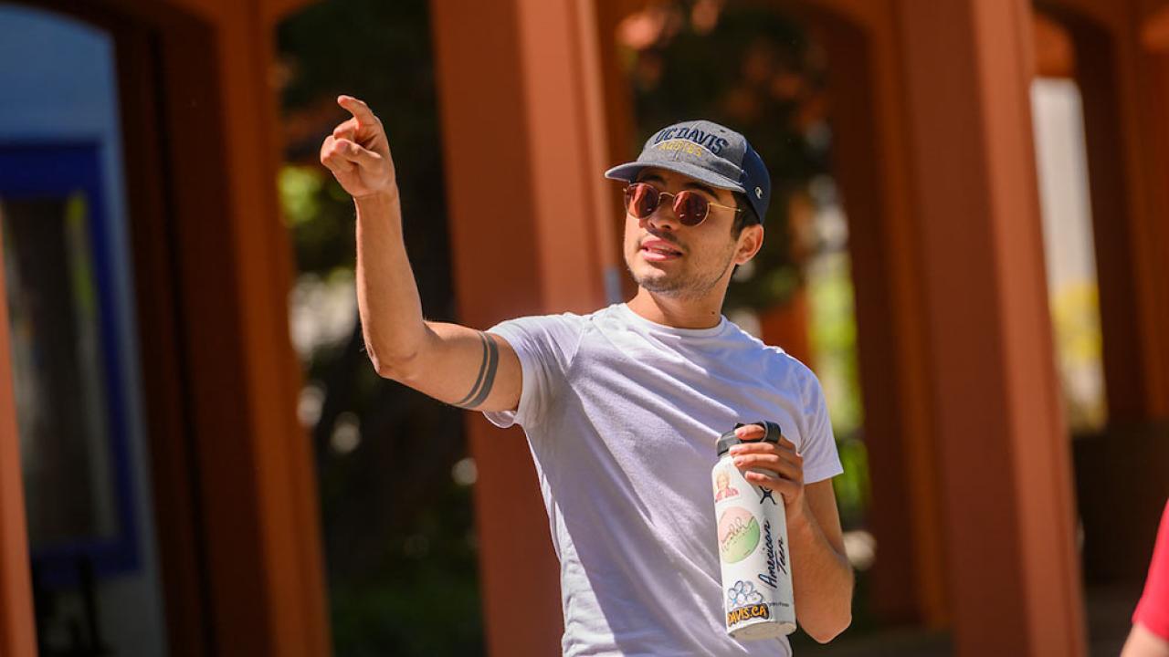 male tour guide pointing out a ֱ campus landmark