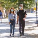Students with masks walk through the sunlit ֱ campus.