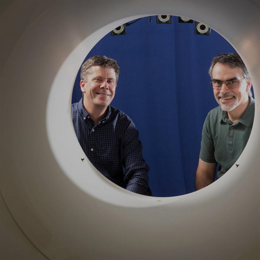 Two researchers stair through the opening to a full body PET scan maching that ֱ pioneered.